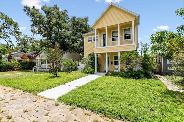 view of front facade with a balcony, a front yard, and a porch