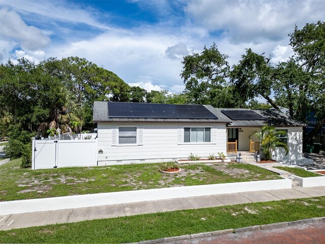 view of front of property with a front lawn and solar panels