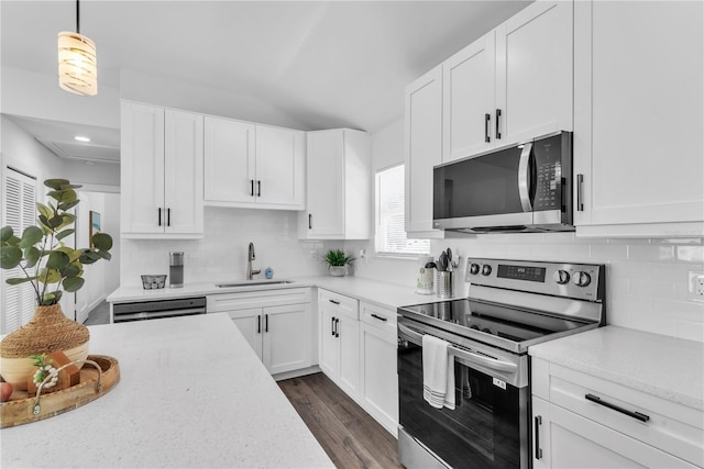 kitchen with white cabinetry, stainless steel appliances, sink, backsplash, and dark wood-type flooring