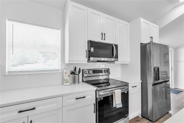 kitchen with appliances with stainless steel finishes, light wood-type flooring, light stone counters, and white cabinetry