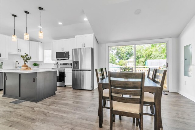 kitchen with white cabinetry, electric panel, light hardwood / wood-style floors, appliances with stainless steel finishes, and pendant lighting