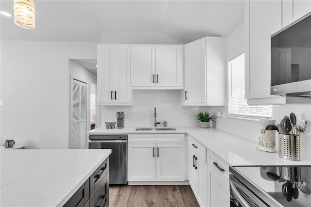 kitchen with tasteful backsplash, light wood-type flooring, white cabinets, stainless steel appliances, and sink