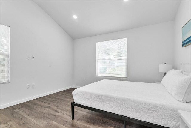 bedroom with wood-type flooring and vaulted ceiling