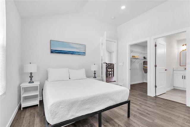 bedroom with a closet, hardwood / wood-style floors, a walk in closet, ensuite bathroom, and lofted ceiling