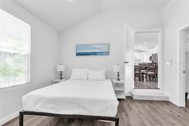 bedroom featuring light wood-type flooring and lofted ceiling