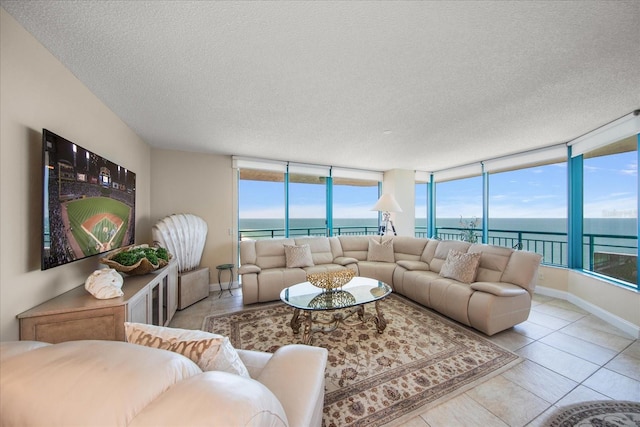 living room with light tile patterned flooring, a water view, a textured ceiling, and a healthy amount of sunlight