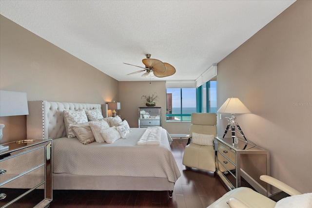 bedroom with a water view, a textured ceiling, ceiling fan, and hardwood / wood-style floors