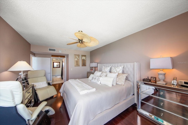 bedroom with a textured ceiling, ceiling fan, and dark hardwood / wood-style floors