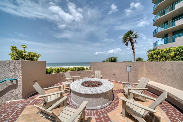 view of patio / terrace with a balcony, a water view, and a fire pit