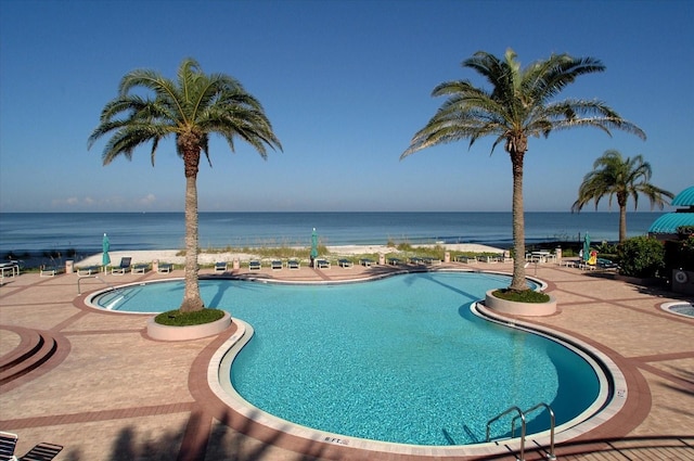 view of pool with a patio area and a water view