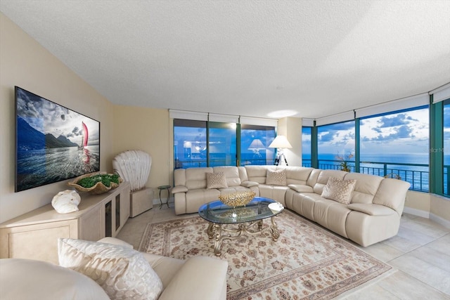 tiled living room featuring expansive windows, a water view, and a textured ceiling