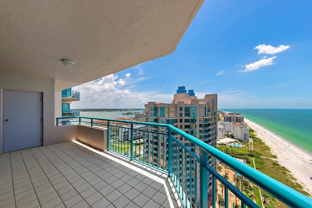 balcony with a water view and a view of the beach