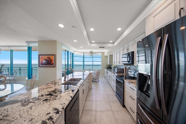 kitchen with sink, white cabinetry, black appliances, and a wealth of natural light