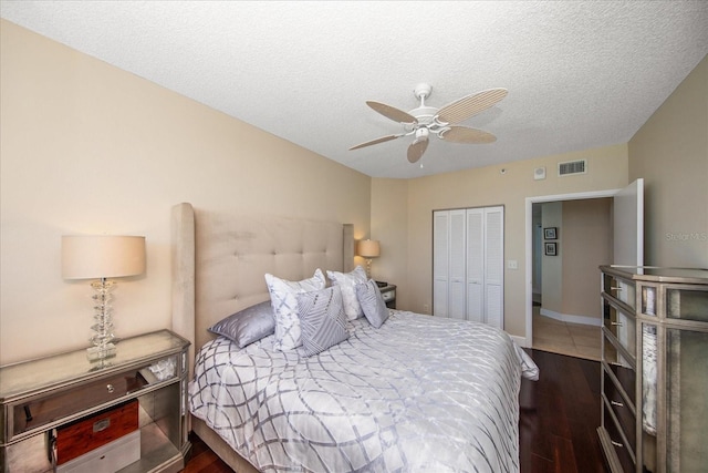 bedroom featuring dark hardwood / wood-style floors, a textured ceiling, a closet, and ceiling fan