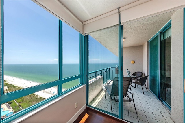 sunroom / solarium with view of water and beach