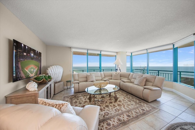 living area featuring a water view, a textured ceiling, tile patterned flooring, healthy amount of natural light, and baseboards