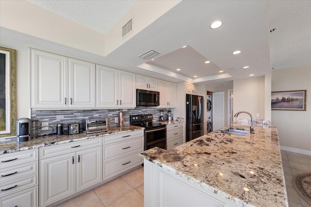 kitchen with a sink, range with electric cooktop, stainless steel refrigerator with ice dispenser, light tile patterned flooring, and a tray ceiling