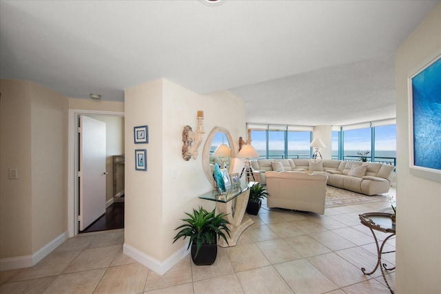 living area with light tile patterned flooring, baseboards, and a water view