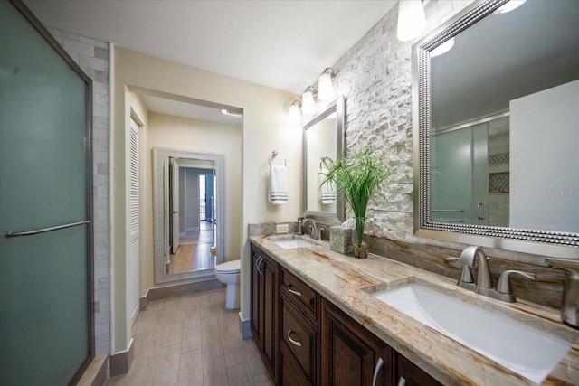 full bath featuring wood finished floors, toilet, a stall shower, baseboards, and double vanity