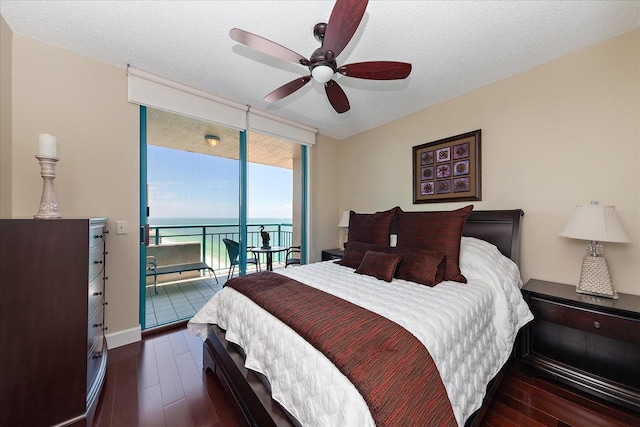 bedroom with access to exterior, wood finished floors, a water view, a ceiling fan, and baseboards