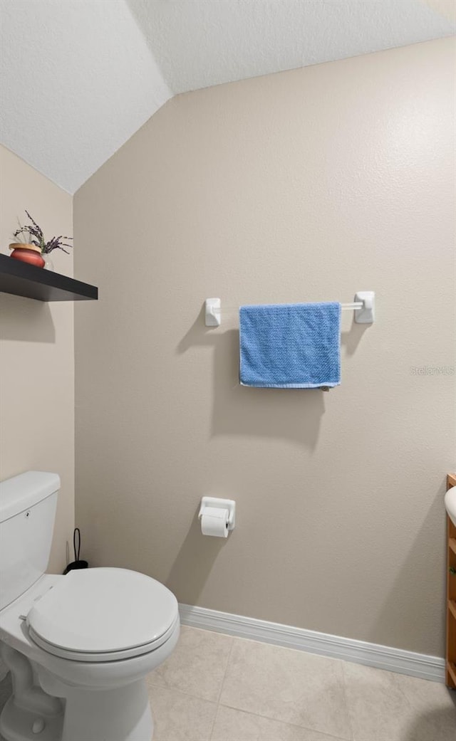 bathroom featuring vanity, tile patterned flooring, toilet, and vaulted ceiling