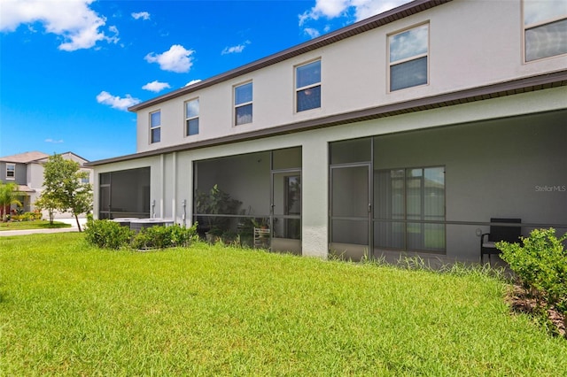 back of property with a sunroom and a yard