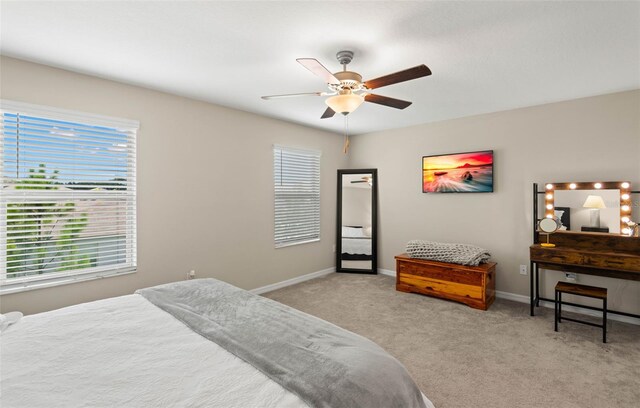 bedroom featuring ceiling fan, multiple windows, and light carpet