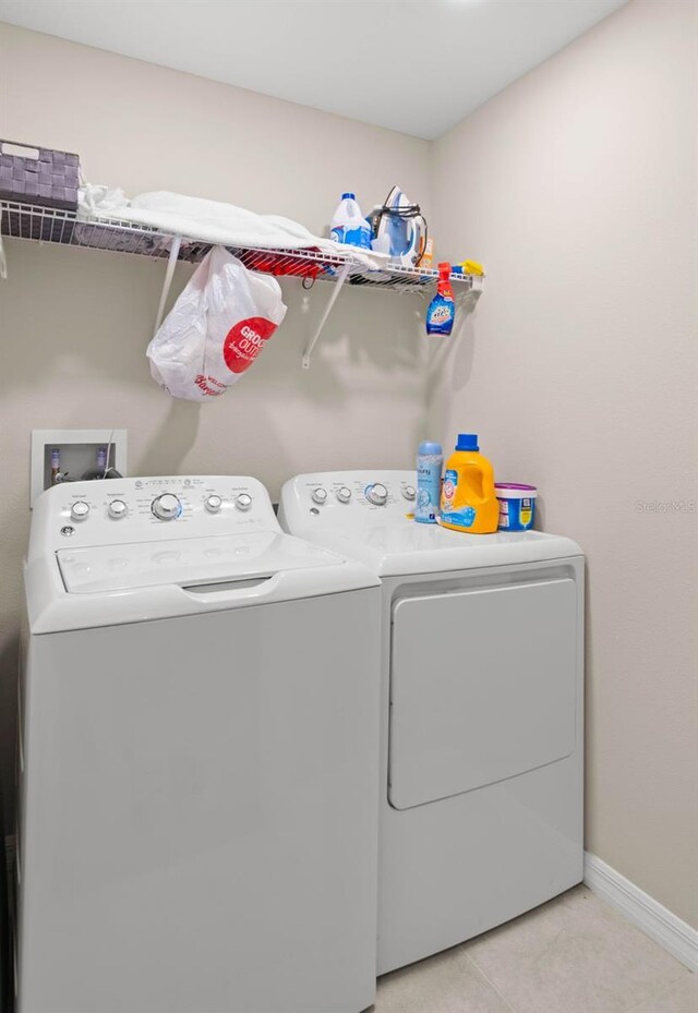 clothes washing area with light tile patterned floors and washer and dryer