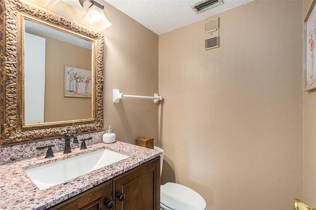 bathroom featuring toilet, vanity, and a textured ceiling