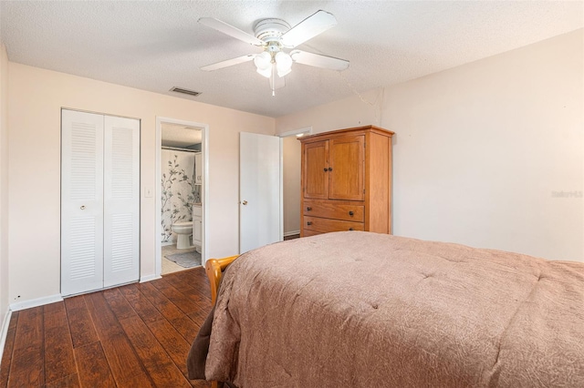 bedroom with a textured ceiling, dark hardwood / wood-style flooring, ceiling fan, a closet, and ensuite bath