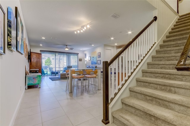 staircase featuring tile patterned floors and ceiling fan