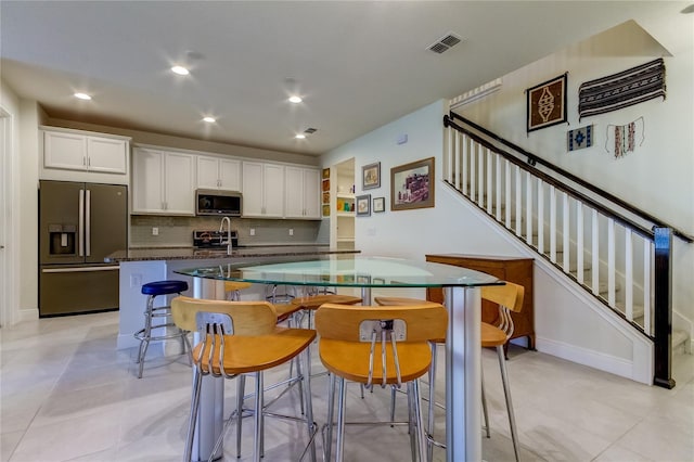 kitchen featuring a kitchen island, a breakfast bar, white cabinetry, sink, and stainless steel appliances