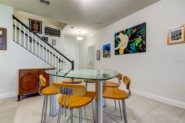 dining space with a textured ceiling and light tile patterned floors