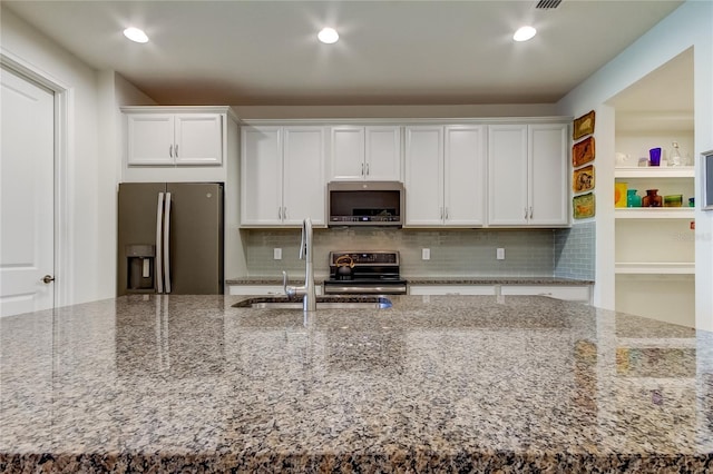 kitchen with white cabinetry, appliances with stainless steel finishes, sink, and light stone counters