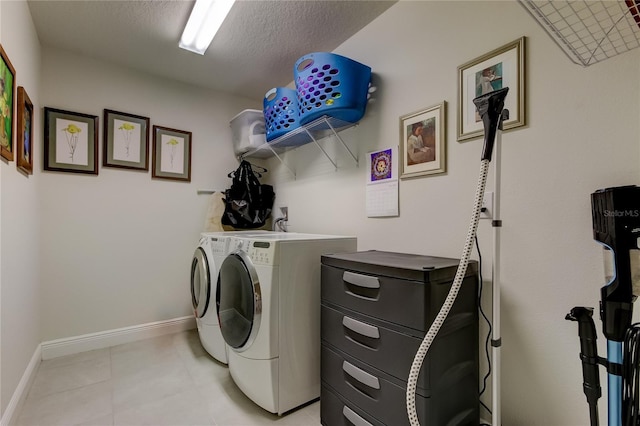 laundry room with light tile patterned flooring, a textured ceiling, and washer and clothes dryer