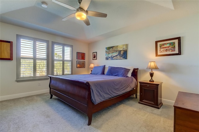 carpeted bedroom with ceiling fan and a raised ceiling