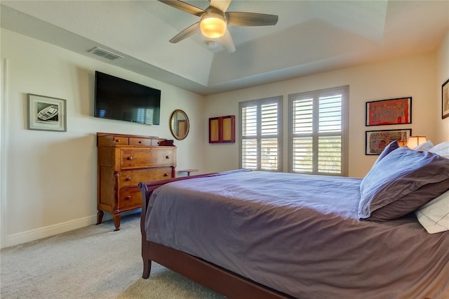 bedroom with light carpet, a raised ceiling, and ceiling fan