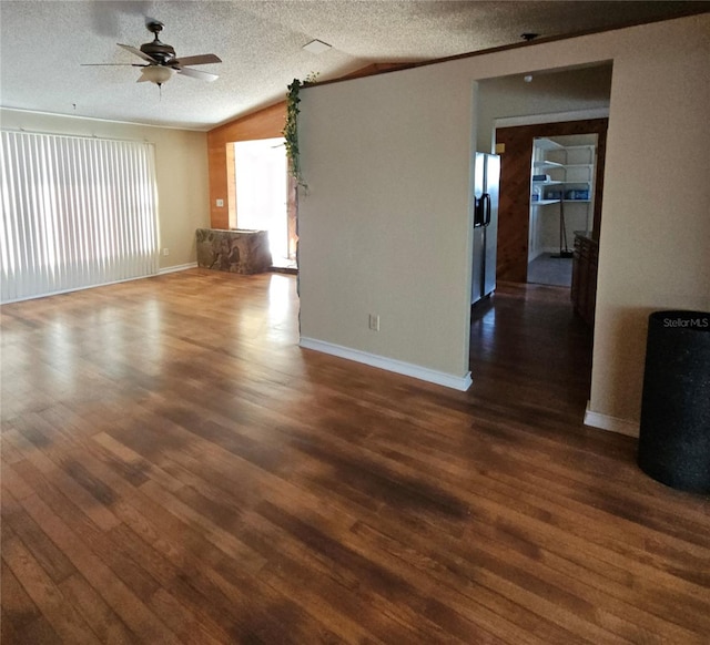 unfurnished living room featuring ceiling fan, dark hardwood / wood-style floors, vaulted ceiling, and a textured ceiling