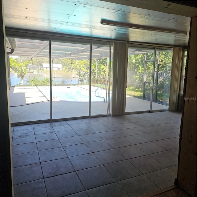 empty room with a wealth of natural light, tile patterned floors, and a water view