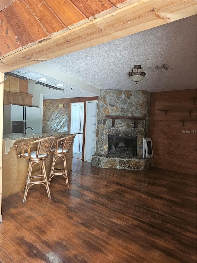 living room with dark hardwood / wood-style floors, a fireplace, a textured ceiling, and wood walls