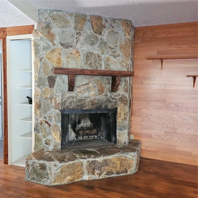 details with wood-type flooring, a fireplace, a textured ceiling, and wood walls