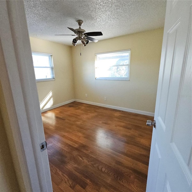 empty room featuring dark wood-type flooring, a textured ceiling, and ceiling fan