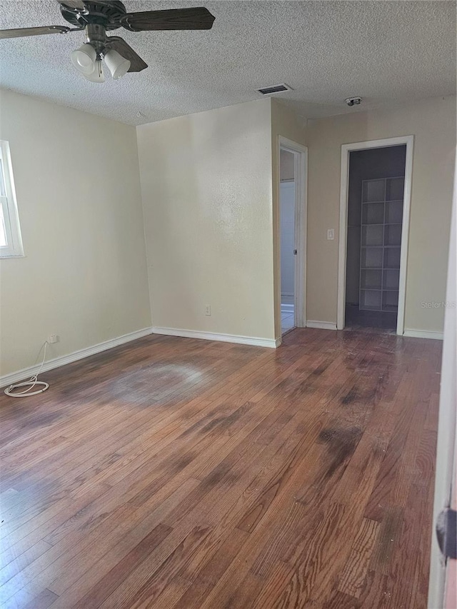 unfurnished room with ceiling fan, wood-type flooring, and a textured ceiling