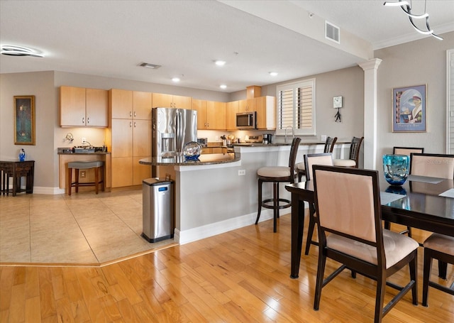 dining area featuring a textured ceiling, light hardwood / wood-style floors, crown molding, and decorative columns