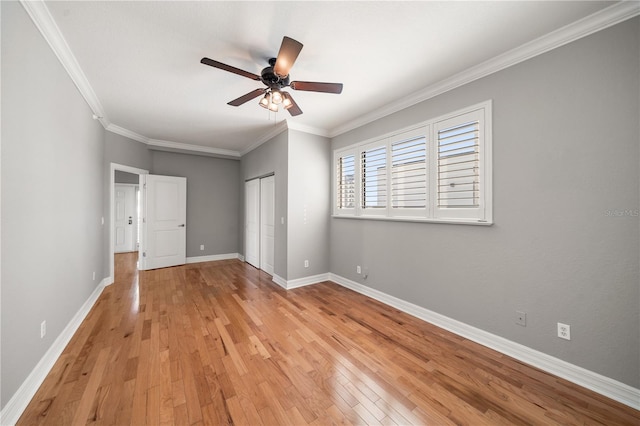 unfurnished bedroom with a closet, baseboards, crown molding, and light wood finished floors