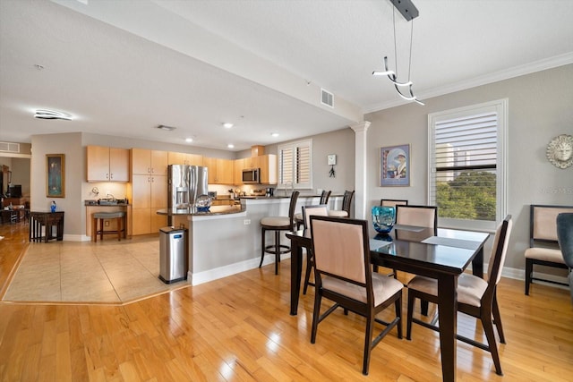 dining room featuring light wood finished floors, baseboards, visible vents, ornamental molding, and ornate columns