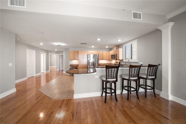 kitchen featuring appliances with stainless steel finishes, light wood-type flooring, visible vents, and a peninsula