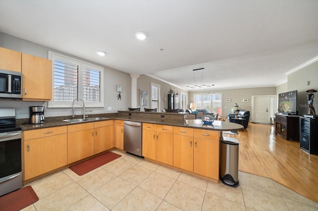 kitchen featuring light tile patterned floors, open floor plan, a peninsula, stainless steel appliances, and a sink