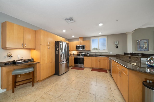 kitchen with stainless steel appliances, visible vents, light tile patterned flooring, a sink, and dark stone countertops