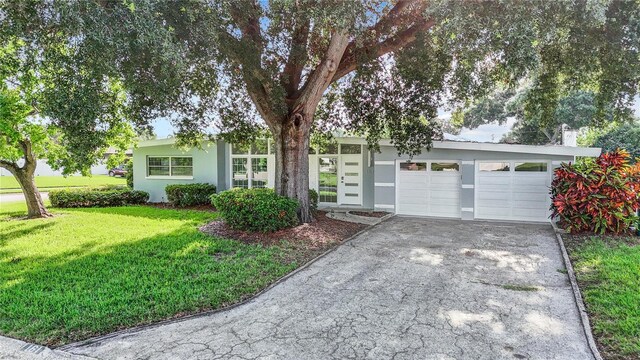 view of front of house with a front yard, driveway, an attached garage, and stucco siding